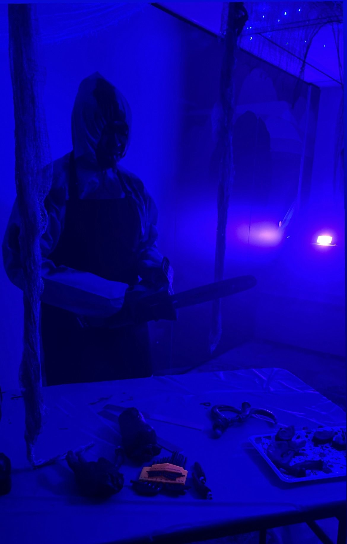 Live scare actor in a blue-lit Halloween room