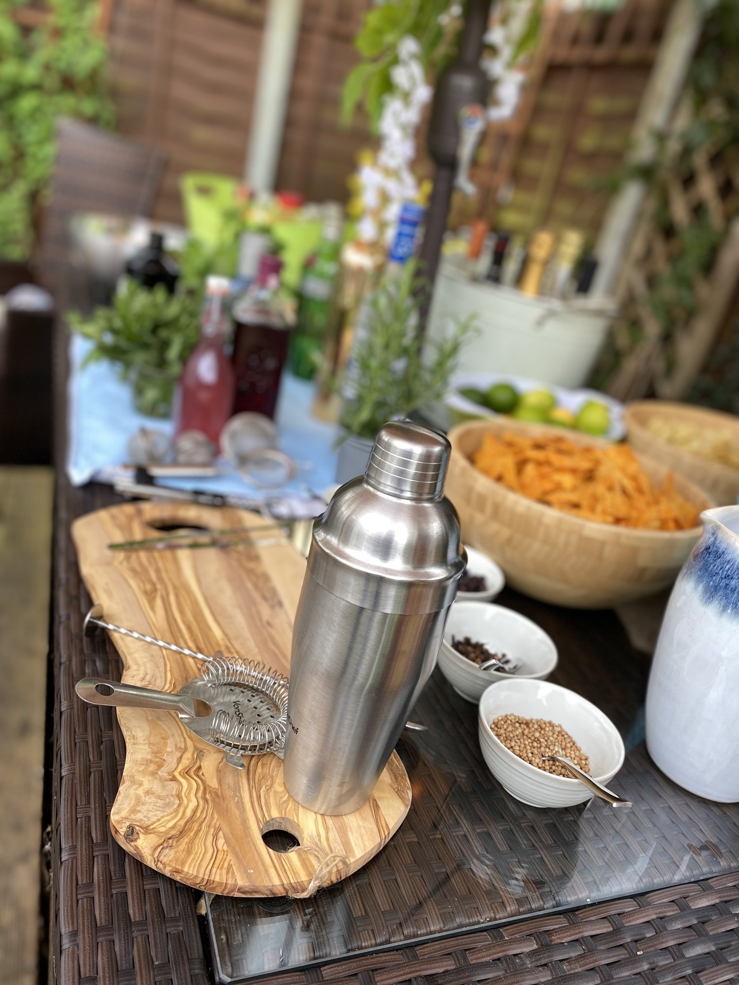 Cocktail shaker and strainer prepared on a wooden bar.